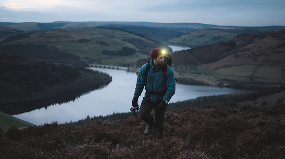 Man hikes with headlamp through rugged mountainous landscape
